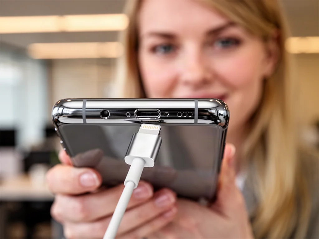 Zbliżenie na port ładowania iPhone'a 14 z wpiętym kablem typu Lightning.